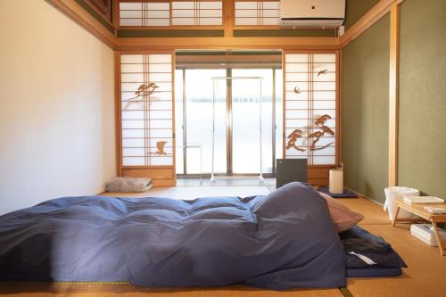 a bedroom with a large bed in front of a window at Lacomaゲストハウスー海と星空にとけこむ癒しの宿 in Esumi