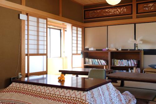 a living room with a table and a book shelf at Lacomaゲストハウスー海と星空にとけこむ癒しの宿 in Esumi