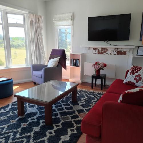 a living room with a red couch and a coffee table at Little Blue Bach in Whanganui