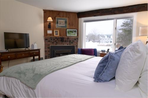 a bedroom with a bed with a television and a fireplace at Brass Lantern Inn in Stowe