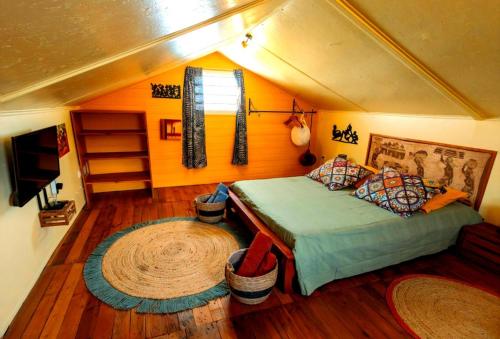 a bedroom with a bed in a room with wooden floors at LE TI CITRON VERT - Baignoire à ciel ouvert et refuge coloré - in Saint-Leu