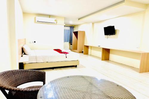 a room with a bed and a table and a tv at Lampang Green Garden Resort in Ban Chomphu