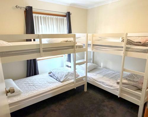 a room with three bunk beds and a window at Serenity on Spry in Port Moonta