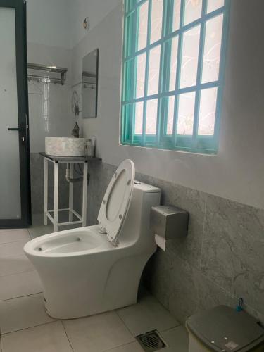 a bathroom with a toilet and a sink and a window at Khách sạn Vườn Bưởi in Ấp Bình Sơn