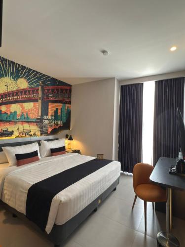 a bedroom with a large bed with a painting on the wall at Azana Style Hotel Tulungagung in Tulungagung