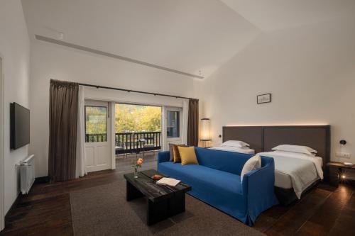 a bedroom with a blue couch and a bed at Mocun Resort in Deqing