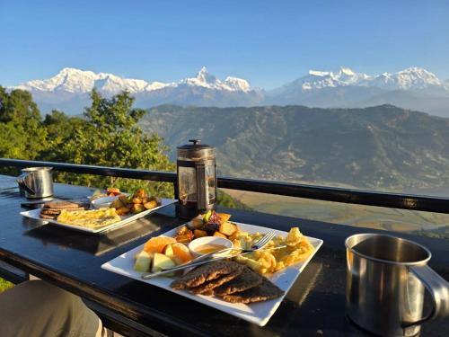 two plates of food on a table with mountains in the background at Pumdikot Mountain Lodge in Pokhara