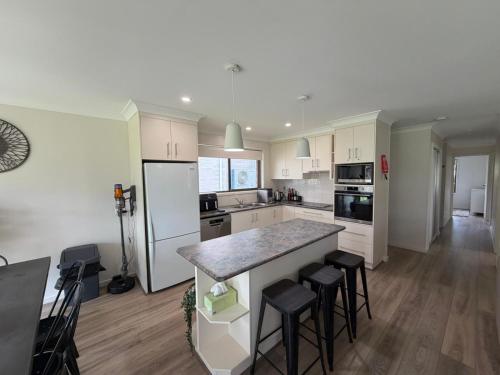 a kitchen with white cabinets and a counter with stools at Mistral Breeze in Nelson Bay