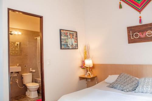 a bedroom with a bed and a bathroom with a toilet at Villana's Hostal Santa Marta in Santa Marta