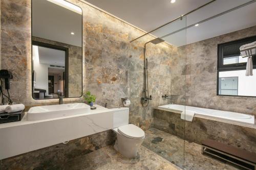 a bathroom with a tub and a toilet and a sink at GrandView Hotel & Residence Hanoi in Hanoi