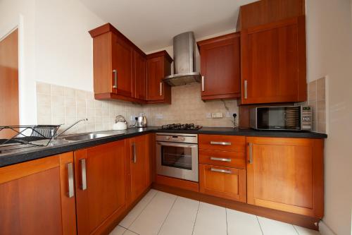 a kitchen with wooden cabinets and a microwave at Spacious 2BDR Flat Near Portmarnock Beach in Dublin