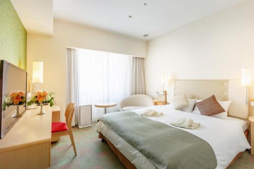 a hotel room with a large bed and a desk at City Plaza Osaka in Osaka