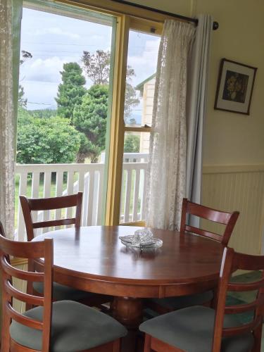 a dining room table with chairs and a large window at Fernbrook Lodge in Dorrigo
