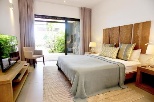 a bedroom with a large bed and a television at Coral Villa in Cap Malheureux