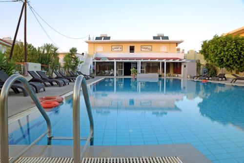a large swimming pool with chairs and a building at Falirala Central in Faliraki