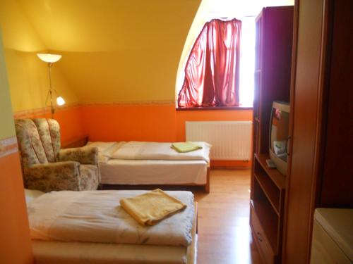 オロシュハーザにあるKertvárosi Vendégházのベッド2台、椅子、窓が備わる客室です。