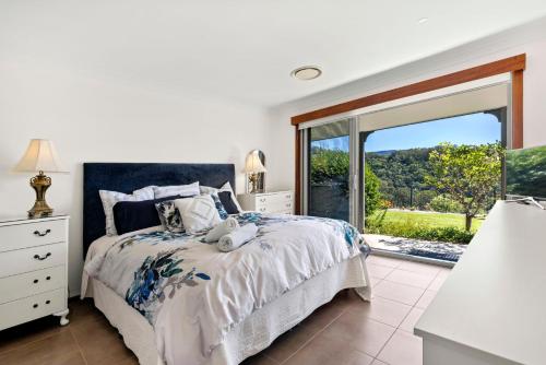 a white bedroom with a bed and a large window at Moonraker - Fireplace with Swimming Pool in Broughton Village
