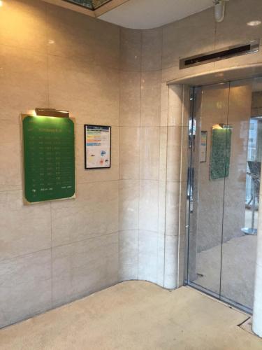 a shower with a green sign on a wall at Hotel New Green Plaza in Nagaoka
