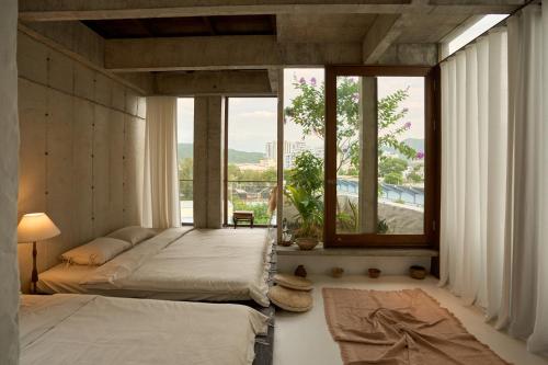 a bedroom with two beds and a large window at The Still Slow & Sip in Nha Trang