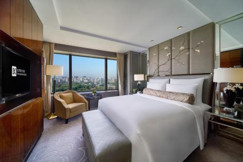 a bedroom with a large white bed and a large window at The Kunlun Beijing Jin Jiang Radisson in Beijing