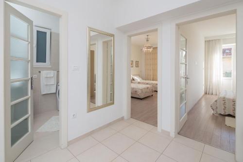 un couloir blanc avec un miroir et une chambre dans l'établissement Apartment Vuko, à Split