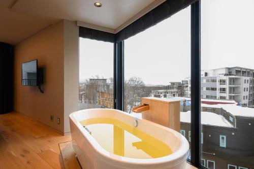 a bath tub in a room with a large window at HOTELA Niseko Towers in Kutchan