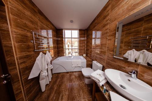 a bathroom with a tub and a toilet and a sink at Hotel Palazzo Krasnodar in Krasnodar