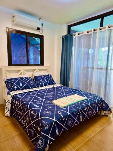 a bedroom with a bed with a blue comforter and a window at Nice Whitepebbles Beach Front in Sibulan
