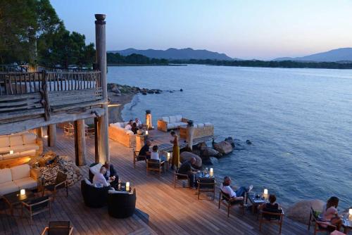 people sitting on a deck next to a body of water at Hôtel Le Belvédère in Porto-Vecchio