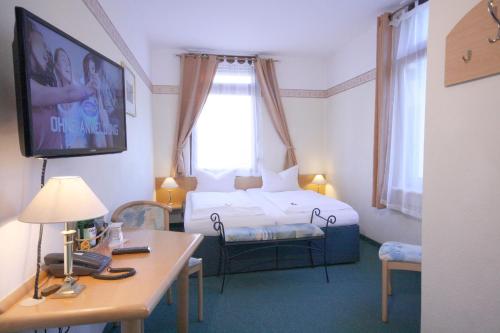a hotel room with a bed and a table and a desk at Classic Inn in Heidelberg