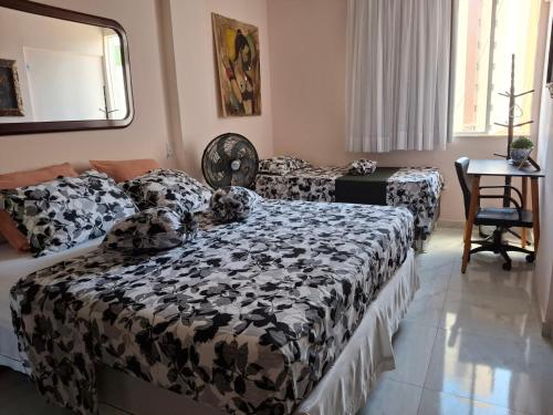 a bedroom with two beds and a table at Hospedagem Porto Barra in Salvador