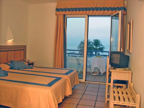 a bedroom with a bed and a television and a balcony at Virgen del Mar Holidays in Mojácar