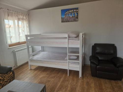 a white bunk bed in a room with a chair at Villa Müller in Poreč