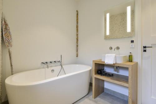 a white bath tub in a bathroom with a mirror at Follow The Sun Apartment in Zandvoort
