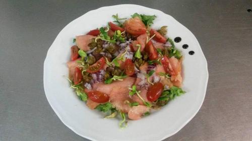 a white plate with a salad with meat and tomatoes at Hotel Korona in Ciechanów