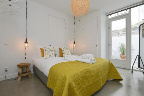 a bedroom with a large bed with a yellow blanket at Follow The Sun Apartment in Zandvoort