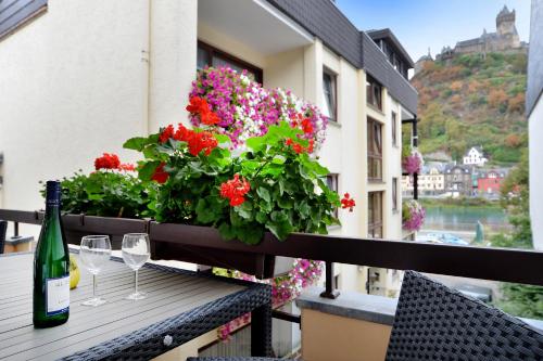 a bottle of wine and glasses on a balcony with flowers at Haus Daniela Superior in Cochem