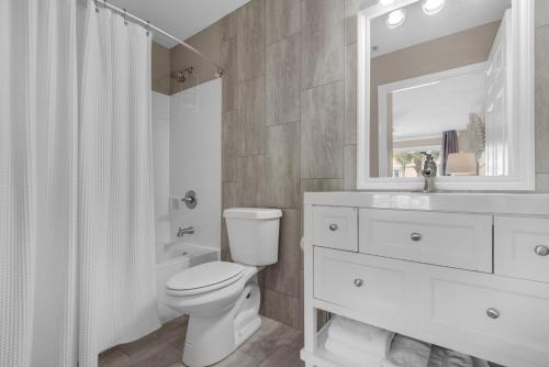a bathroom with a toilet and a sink and a mirror at Emerald Gulf Escape at Miramar Beach in Destin