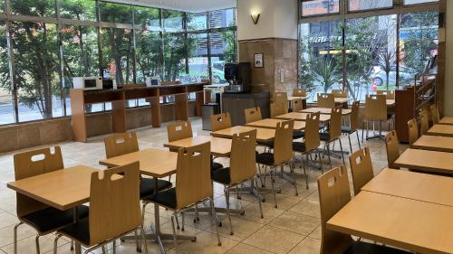 a restaurant with wooden tables and chairs and windows at Toyoko Inn Kumamoto Shin-shigai in Kumamoto