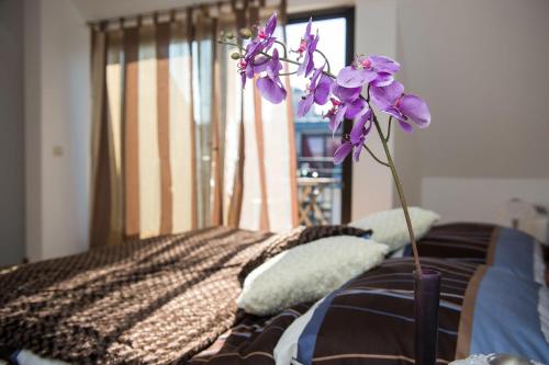 a vase with purple flowers sitting on a bed at Budapest Center Residence in Budapest