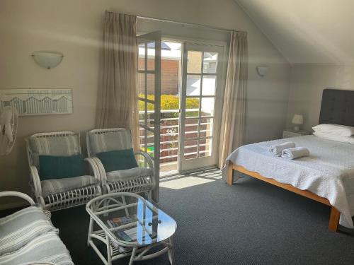 a bedroom with a bed and chairs and a balcony at Fremantle Local Beach Studio in Fremantle
