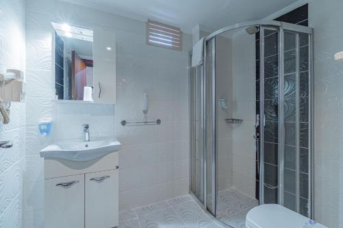 a white bathroom with a shower and a sink at Grand Barhan Hotel Alanya in Alanya