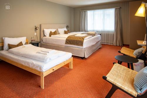 a hotel room with two beds and a chair at Hotel Bergidyll - Riders Haven - Self Check In in Andermatt