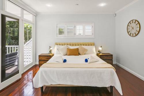 a bedroom with a bed and a clock on the wall at Willow Garden Stays Cairns - Beachfront 4 Bedroom Luxury Holiday Home in Kewarra Beach