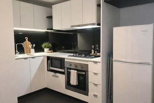 a white kitchen with a stove and a refrigerator at Breathtaking views of Yarra River and City skyline with Gym access in Melbourne