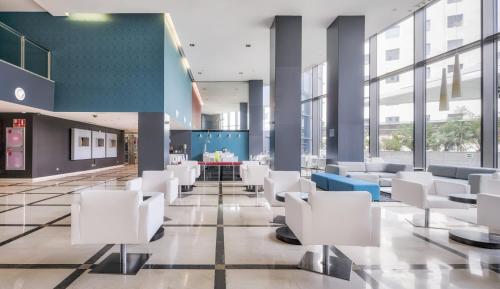 a lobby with white chairs and a table at Ilunion Aqua 4 in Valencia