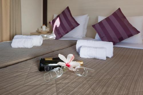 Una botella de vino y una flor en una cama en Francoise Hotel, en Galissas