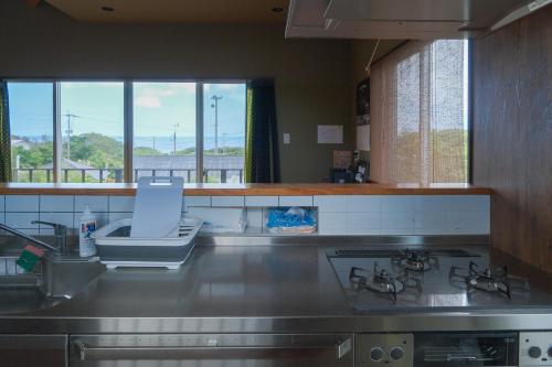 a kitchen with a sink and a stove and windows at スローライフ喜界 in Onozu