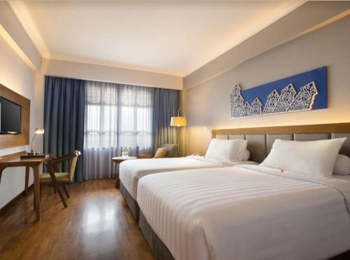 a hotel room with two beds and a desk at Monopoli Hotel Bukittinggi in Bukittinggi