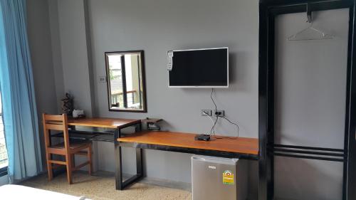 a room with a desk and a television on a wall at ChomTrang in Trang